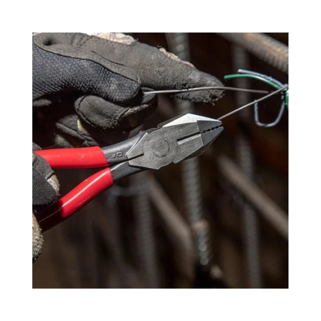 Pinzas de electricista sujetando alambre con mordazas metálicas y mango rojo